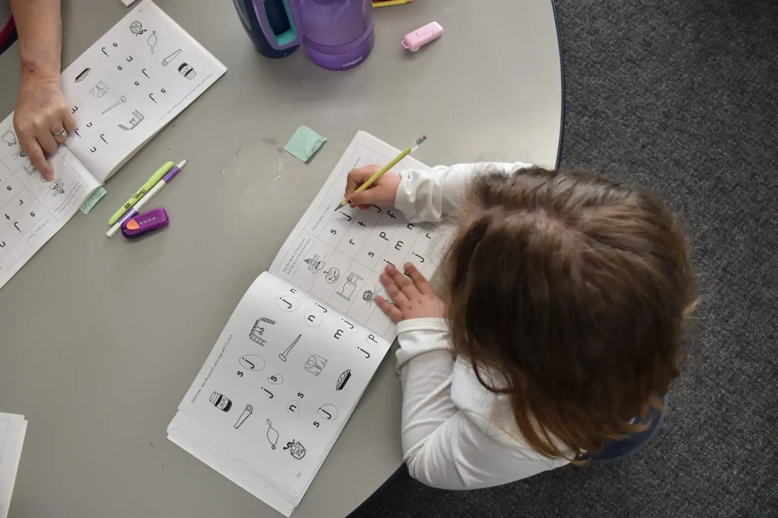 A young student tracing letters on a worksheet