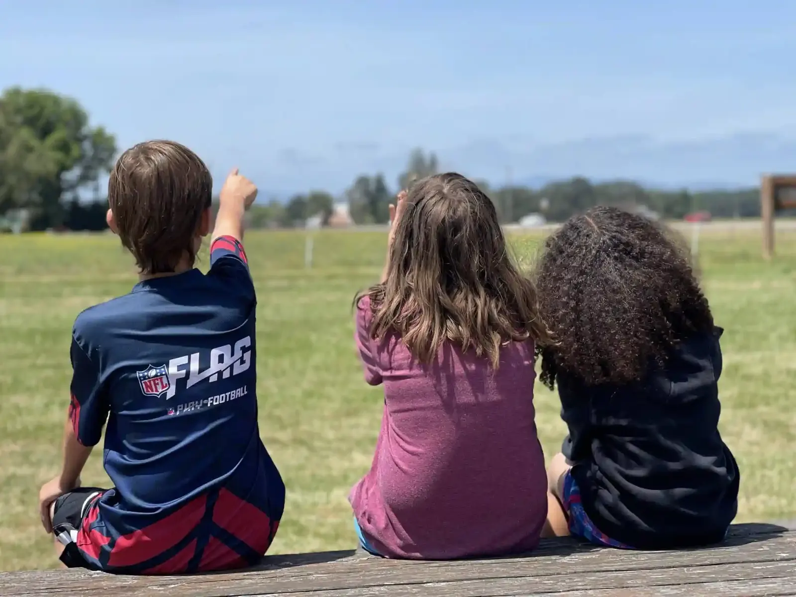 Three students sitting together looking out over the school field